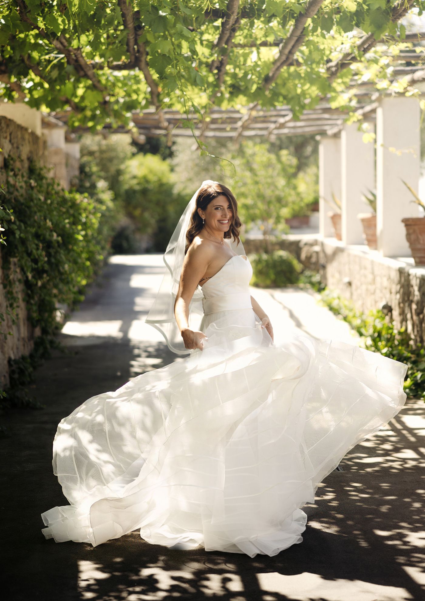 La sposa gira su se stessa sotto un pergolato, il velo e la gonna in movimento